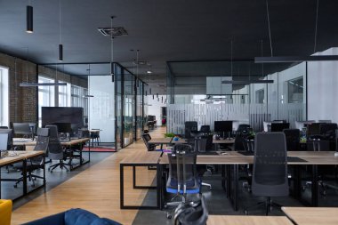 Minimalist tasarım, siyah sandalyeler, ahşap masalar ve cam bölümler ile çağdaş açık uzay ofis iç mimarisi profesyonel bir şirket çalışma ortamını temsil etmektedir.