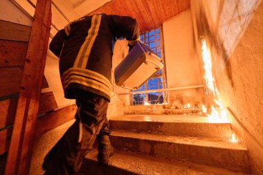 Bir bina yangını sırasında portatif bir kafeste kurtarılan kediyi taşıyan cesur itfaiyeci hem insan hem de hayvanın hayatını kurtarma cesaretini, şefkatini ve bağlılığını simgeliyor.