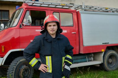 Bir itfaiyeci kırmızı bir itfaiye aracının önünde duruyor, acil müdahale için hazır. Bu resim, güvenlik ve kurtarma temalarını resmetmeye uygun itfaiyecilerin azim ve cesaretini gösteriyor.