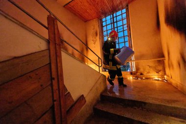 Bir bina yangını sırasında portatif bir kafeste kurtarılan kediyi taşıyan cesur itfaiyeci hem insan hem de hayvanın hayatını kurtarma cesaretini, şefkatini ve bağlılığını simgeliyor.