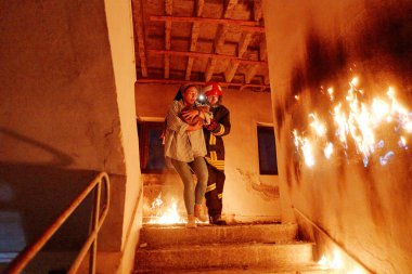 İki cesur itfaiyeci, bir acil kurtarma operasyonu sırasında kahramanlık, şefkat ve takım çalışmasını simgeleyen yanan binadan kedisini güvenli bir yere taşıyan korkmuş bir kadına yardım ediyor.