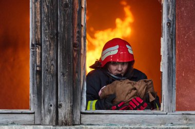 Bir itfaiyeci yanan bir binadan bir bebeği kurtarıyor. İtfaiyeci harekete geçti, çocuğu acil durumdan kurtardı. Bu görüntü cesaret ve kurtarma temalarını göstermek için kullanılabilir.