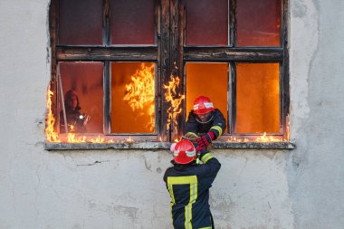 Bir itfaiyeci yanan bir binadan bir bebeği kurtarıyor. İtfaiyeci harekete geçti, çocuğu acil durumdan kurtardı. Bu görüntü cesaret ve kurtarma temalarını göstermek için kullanılabilir.