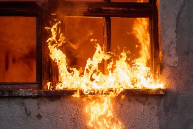 Bir pencere alevler içinde, bir felaket sahnesini ve yangın tehlikesini gösteriyor. Bu resim acil durumlar, mülke zarar vermek ve yangın güvenliğinin önemini göstermek için uygundur..