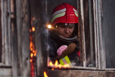 Bir itfaiyeci yanan bir binadan bir bebeği kurtarıyor. İtfaiyeci harekete geçti, çocuğu acil durumdan kurtardı. Bu görüntü cesaret ve kurtarma temalarını göstermek için kullanılabilir.