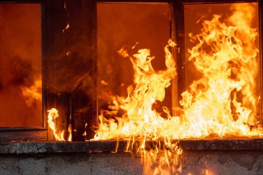 Yanan bir binanın dramatik bir görüntüsü. Pencereleri alevler kaplıyor. Bu fotoğraf felaket, acil durumlar, yıkım ve ateşin gücü gibi kavramları göstermek için kullanılabilir. Şey...