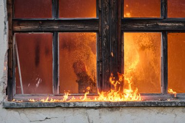 Yanan bir binanın dramatik görüntüsü, eski bir pencereyi saran alevler. Bu fotoğraf yangın felaketi, yıkım, tehlike ve acil durumlar gibi kavramları göstermek için kullanılabilir. Bu uygun.