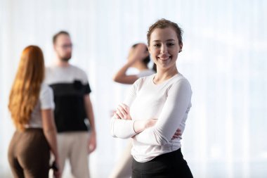 Kolları çapraz duran ve kameraya gülümseyen kendine güvenen bir kadının portresi.