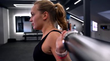 Bir fitness meraklısı modern bir spor salonunda güç antrenmanı yapar. Halter kaldırıyor, vücuduna ve egzersizine odaklanıyor..