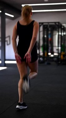Kararlı bir atlet modern bir spor salonunda güçlü eğitim ekipmanlarıyla yüksek diz koşusu yapar. Sabah ışığı, egzersiz rutinini uygularken dikkatini dağıtıyor..