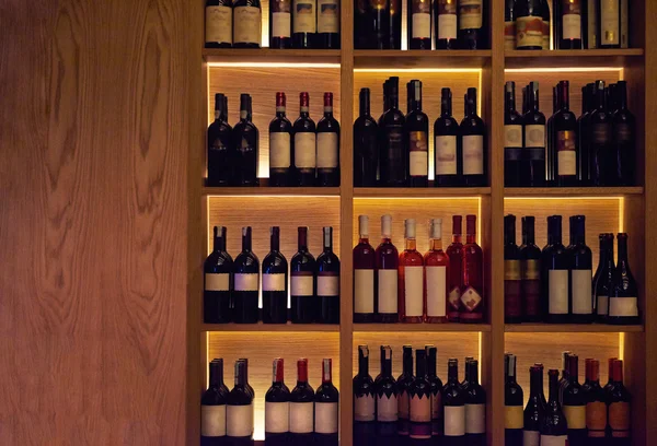 Wine bottles on a wooden shelf. — Stock Photo, Image