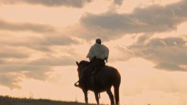 Büyük siyah bir at üzerindeki bir Viking savaşçısının sinematik hava drone 'u günbatımında dramatik bir manzarayı inceler, Antik keşif, macera ve ruhun kürk pelerinini giyer.
