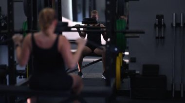 Spor salonunda egzersiz yapan bir insan otururken vücudunun üst kısmını kaldırır. Antrenman sırasında atmosfer enerji dolu, kendini adamış ve güç kazanma çabaları gösteriyor..