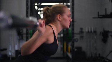 Kendini spora adamış bir sporcu spor salonunda ağırlık kaldırma antrenmanına başlar, halterle çömelirken doğru tekniğe konsantre olur. Çevre ciddi egzersizler için donatılmıştır..