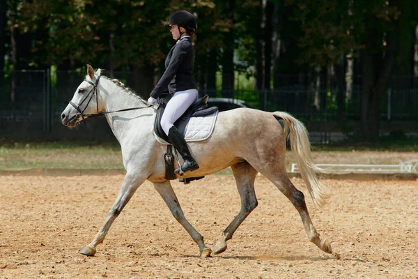At biniciliği yarışında ata binen bir kadın binicilik sporlarındaki eğitim ve becerilerini sergiliyor. Bu resim atletizm, açık hava aktivitelerinin temaları ve