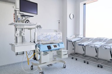 İyi ışıklandırılmış bir yenidoğan bakım ünitesinde, iki kuluçka makinesi bir tıbbi monitör ve ilave ekipmanın yanına yerleştirilir. Oda, yeni doğan bakımı için temiz yüzeyler ve düzenli alanlar içeriyor..