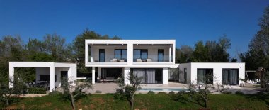 Havuzu, terasları ve insansız hava aracı tarafından yakalanan temiz minimalist mimarisi olan modern lüks villa. Parlak güneşli bir gün, çevreleyen yeşillikler, ve çağdaş açık yaşam alanları.