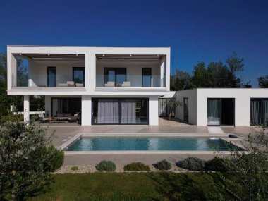 Havuzu, terasları ve insansız hava aracı tarafından yakalanan temiz minimalist mimarisi olan modern lüks villa. Parlak güneşli bir gün, çevreleyen yeşillikler, ve çağdaş açık yaşam alanları.