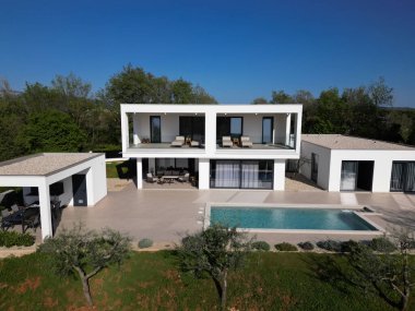 Havuzu, terasları ve insansız hava aracı tarafından yakalanan temiz minimalist mimarisi olan modern lüks villa. Parlak güneşli bir gün, çevreleyen yeşillikler, ve çağdaş açık yaşam alanları.
