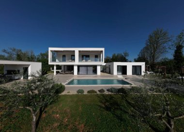 Havuzu, terasları ve insansız hava aracı tarafından yakalanan temiz minimalist mimarisi olan modern lüks villa. Parlak güneşli bir gün, çevreleyen yeşillikler, ve çağdaş açık yaşam alanları.