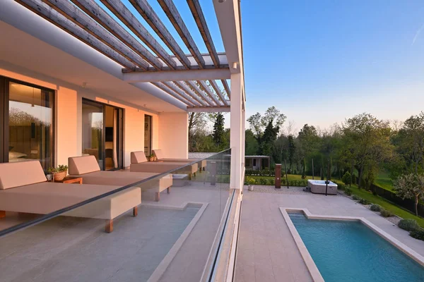 Güneşli bir günde havuzu, terası ve minimalist mimarisi olan modern lüks villa. Temiz hatlar, geniş pencereler ve açık yaşam alanları modern ev ortamları oluşturur..