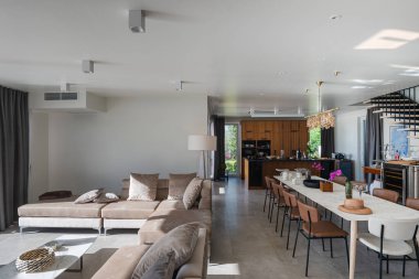 İçinde yüzen merdiven, mermer yemek masası, ahşap mutfak ve bej kanepe bulunan modern lüks iç mimari. Zarif ışıklandırması ve gri döşemeleri olan geniş çağdaş ev tasarımı..