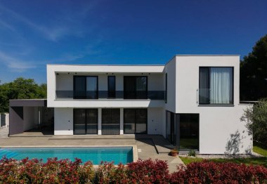 İki çarpıcı modern lüks villanın havadan görünüşü özel yüzme havuzları, zarif mimarisi ve yemyeşil peyzaj, güzel doğal bir zemine karşı kurulmuş..