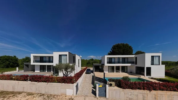 İki çarpıcı modern lüks villanın havadan görünüşü özel yüzme havuzları, zarif mimarisi ve yemyeşil peyzaj, güzel doğal bir zemine karşı kurulmuş..