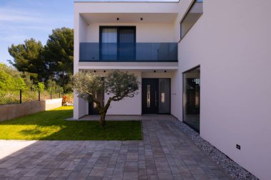 Minimalist mimarisi, ön kapısı, bisikleti ve peyzaj bahçesiyle modern yerleşim yeri girişi. Çağdaş ev dış görünüş temiz tasarım, günlük yaşam tarzı ve açık hava yaşam.
