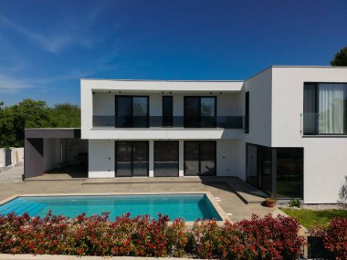 İki çarpıcı modern lüks villanın havadan görünüşü özel yüzme havuzları, zarif mimarisi ve yemyeşil peyzaj, güzel doğal bir zemine karşı kurulmuş..