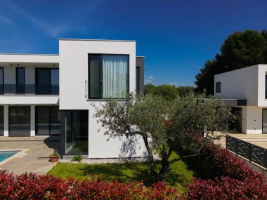 İki çarpıcı modern lüks villanın havadan görünüşü özel yüzme havuzları, zarif mimarisi ve yemyeşil peyzaj, güzel doğal bir zemine karşı kurulmuş..