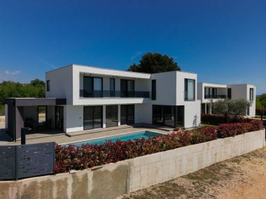 İki çarpıcı modern lüks villanın havadan görünüşü özel yüzme havuzları, zarif mimarisi ve yemyeşil peyzaj, güzel doğal bir zemine karşı kurulmuş..