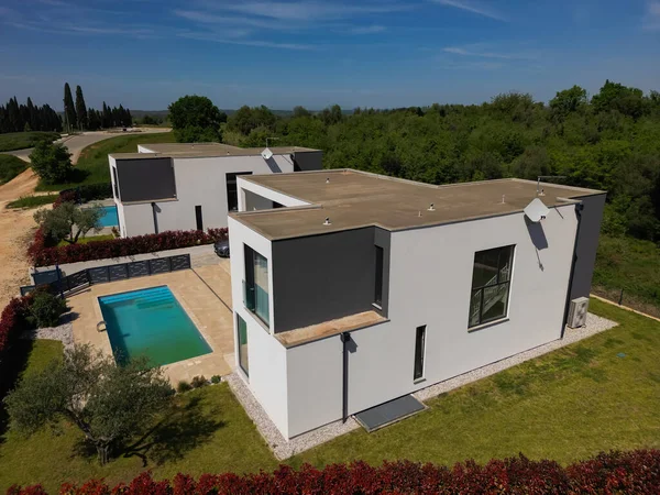 İki çarpıcı modern lüks villanın havadan görünüşü özel yüzme havuzları, zarif mimarisi ve yemyeşil peyzaj, güzel doğal bir zemine karşı kurulmuş..