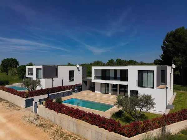 İki çarpıcı modern lüks villanın havadan görünüşü özel yüzme havuzları, zarif mimarisi ve yemyeşil peyzaj, güzel doğal bir zemine karşı kurulmuş..