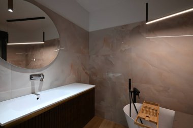 Şatafatlı modern banyo, gösterişli serbest küvet, lavabosu ve aynası olan zarif bir makyaj malzemesi ve modern tuvaleti var. Yumuşak kiremitli duvarlar ve ahşap döşemeler kaplıcaya benzer.