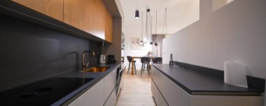 Konforlu bir kanepe, şık koltuklar ve bar boy yemek masası bulunan entegre bir mutfağı olan modern açık planlı yaşam ve yemek alanı. Ahşap zemin ve tavan kirişleri bunu güçlendirir.