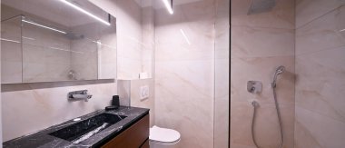 Şatafatlı modern banyo, gösterişli serbest küvet, lavabosu ve aynası olan zarif bir makyaj malzemesi ve modern tuvaleti var. Yumuşak kiremitli duvarlar ve ahşap döşemeler kaplıcaya benzer.