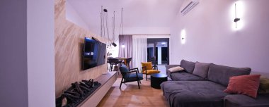 Konforlu bir kanepe, şık koltuklar ve bar boy yemek masası bulunan entegre bir mutfağı olan modern açık planlı yaşam ve yemek alanı. Ahşap zemin ve tavan kirişleri bunu güçlendirir.