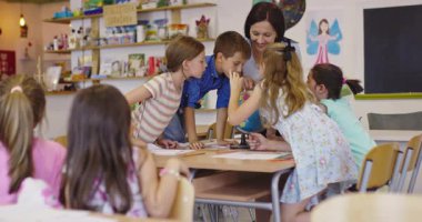 Bir sınıfta fen dersi sırasında bir grup meraklı ilkokul öğrencisine cam kavanozda teraryum bitkisini gösteren bayan öğretmen interaktif öğrenme ve keşfi teşvik ediyor. Sinema yavaşlığı