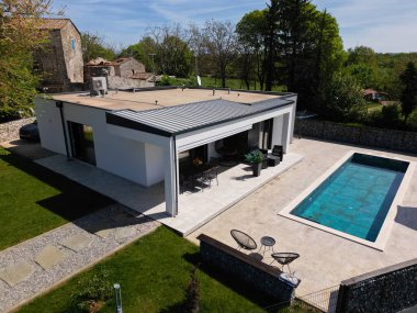 Düz çatısı, yüzme havuzu ve verandası olan modern modüler bir evin havadan görünüşü. Sürdürülebilir tasarım ve açık hava yaşam alanı içeren çağdaş prefabrik ev mimarisi.