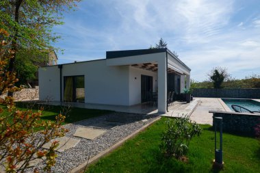 Yemek masası olan, yüzme havuzu ve çitlere bakan modern modüler bir evin terası. Dış mekanı olan çağdaş prefabrik ev mimarisi.