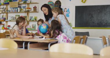 Öğretmen ve ilkokul öğrencileri sınıfta coğrafya öğreniyor, meraklı çocuklar birlikte dünya haritasını keşfediyorlar, sosyal bilimler ve çocuklar için küresel eğitim. Sinematik ağır çekim