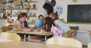 Öğretmen ve ilkokul öğrencileri sınıfta coğrafya öğreniyor, meraklı çocuklar birlikte dünya haritasını keşfediyorlar, sosyal bilimler ve çocuklar için küresel eğitim. Sinematik ağır çekim