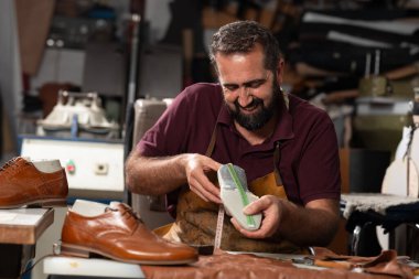 Yetenekli bir ayakkabıcı, yoğun bir atölyede kahverengi bir deri ayakkabıyı parlatır ve ölçer. Gösteriş sanatını, hassasiyetini ve adanmışlığını aletler ve deri kırıntıları arasında gösterir..