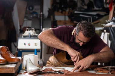 Yetenekli bir ayakkabıcı, yoğun bir atölyede, alet ve yapıştırıcı kullanarak, deri ayakkabılar üzerinde dikkatle çalışır. Sahne, işçiliği, odaklanmayı ve el yapımı deri ayakkabıların dokunsal dokunuşunu yakalıyor..