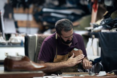 Meşgul bir atölyede ayakkabı tamircisi, detaylara özen gösteren kahverengi bir deri ayakkabı yapar. Deri bir stüdyoda geleneksel el sanatları, konsantrasyon ve profesyonel işçilik sergiler..