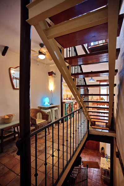 Ahşap merdiveni, eski mobilyaları ve sıcak ışıklandırması olan çok katlı bir iç mekan. Yaşam tarzı, dekorasyon ve iç tasarım temalarına uygun rahat bir ev atmosferi yaratıyor..