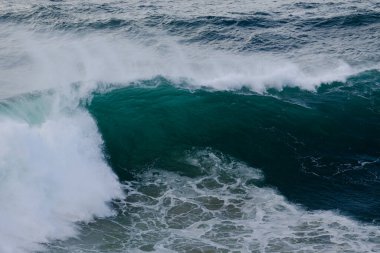 Güçlü bir okyanus dalgası, içi boş, turkuaz su ve beyaz köpüğe dönüşür. Dinamik deniz manzarası enerji, hareket ve doğayı taşır ham güç, doğa, seyahat ve spor temaları için idealdir..