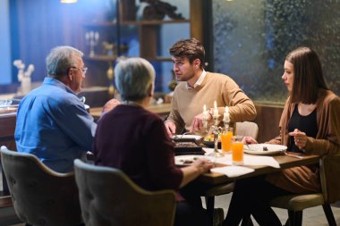 Müslüman bir aile, Ramazan ayında oruç tutmak için bir restoranda toplanıyor. Ilık ışıklandırma mevcut dekorasyonlarla şenlikli atmosferi güçlendirir.