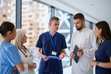 Bir grup sağlık uzmanı, hasta bakımı stratejilerini tartışmak üzere parlak ve modern bir hastanede toplandı. Ekip, önemli kararlarda işbirliği yapan doktor ve hemşireleri de içeriyor..